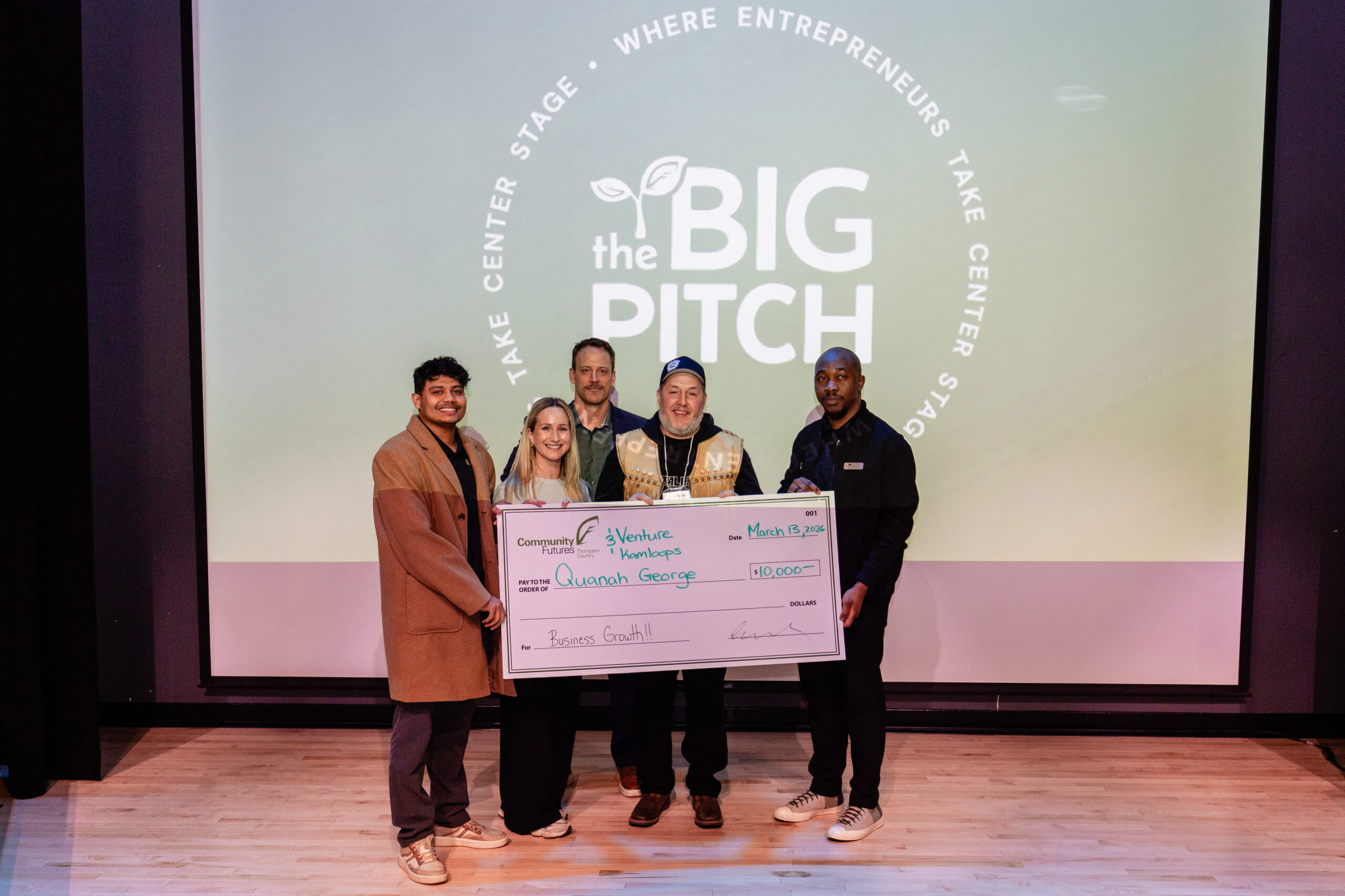Community Futures Thompson Country and Venture Kamloops team members pose with the BIG Pitch grand prize winner, who is holding a ceremonial cheque.